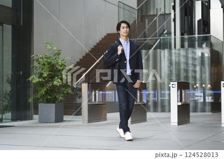 ビジネスリュックを持ってオフィスビルのロビーを歩く若いビジネスマン 124528013