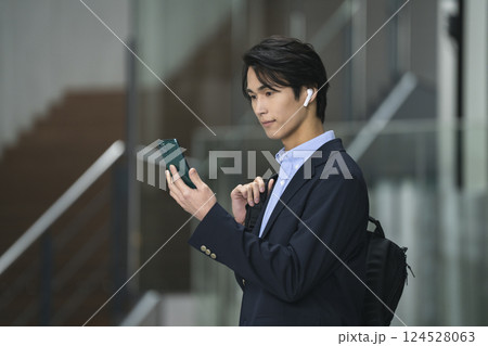 スマホの画面を見るイヤホンをした若いビジネスマン 124528063