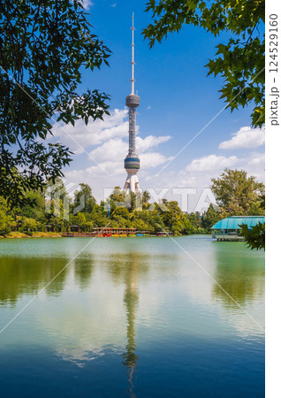 tall television tower in Tashkent in Uzbekistan against the background of a blue sky with a reflection in pond water 124529160