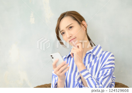 スマホを見て悩み中の女性 124529608