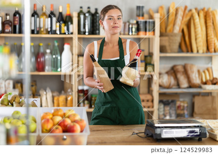 Young female seller offering wine in grocery store 124529983