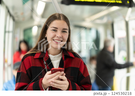 Girl is standing with phone in tram car, getting to work 124530218