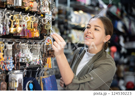Happy female tourist looking to buy tourist keyrings at gift shop Happy female tourist looking to buy tourist keyrings at gift shop 124530223