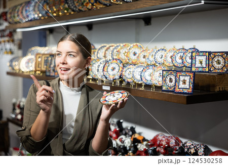 Young woman chooses decorative clock at souvenir market 124530258