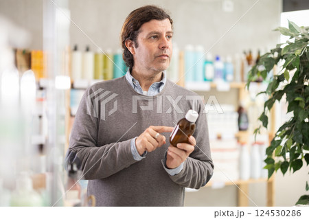 Man choose antitussive syrup in pharmacy Man choose antitussive syrup in pharmacy 124530286