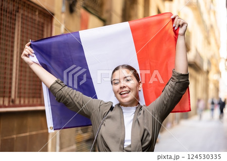 Happy female tourist walking old streets with flag of france Happy female tourist walking old streets with flag of france 124530335