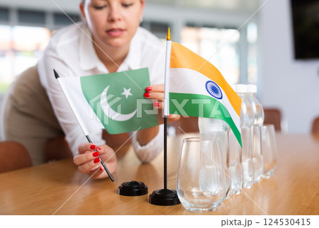 Unrecognizable girl sets midget flags of India and Pakistan before international negotiations 124530415