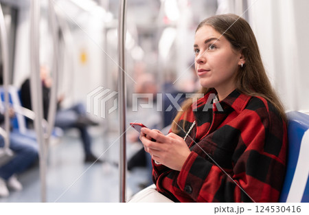girl sitting in subway car with phone girl sitting in subway car with phone 124530416