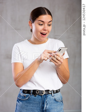 Cheerful young woman looking gladly at mobile Cheerful young woman looking gladly at mobile 124530417