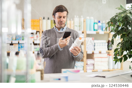 Man in pharmacy scans QR code on emollient cream product Man in pharmacy scans QR code on emollient cream product 124530446