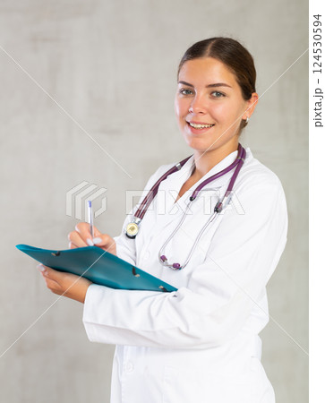 Female doctor makes notes in documents holding a folder of papers in her hands Female doctor makes notes in documents holding a folder of papers in her hands 124530594