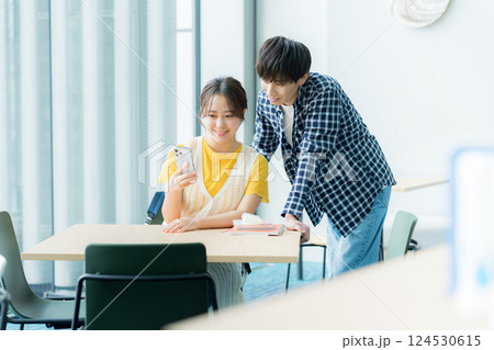 スマホを見ながら話す学生たち 124530615