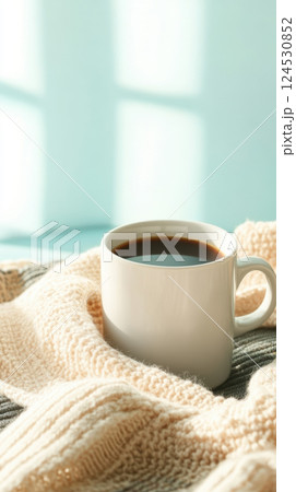 cozy coffee cup on soft knit blanket in warm sunlight 124530852