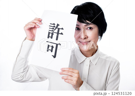 許可と書かれた紙を掲げ微笑む中年女性 124531120