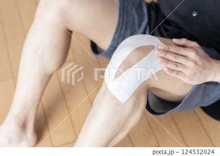 膝に湿布を貼る男性　膝痛　捻挫　関節痛　ボディパーツ 124532024