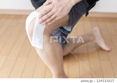 膝に湿布を貼る男性　膝痛　捻挫　関節痛　ボディパーツ 124532027