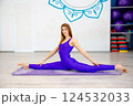 Woman performing a full split yoga pose on a mat in a yoga studio 124532033