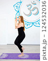 Woman practicing eagle pose (Garudasana) in a yoga studio 124532036