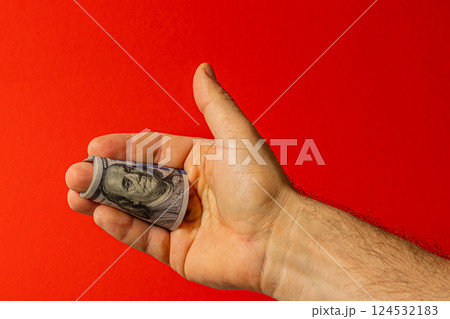 Dollar bill held in hand against a red background Dollar bill held in hand against a red background 124532183