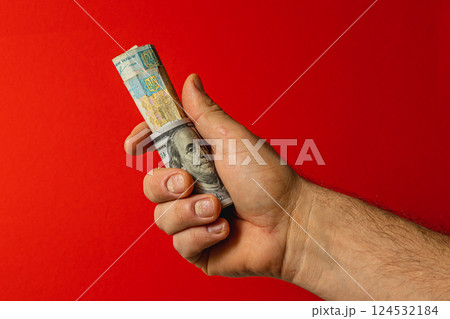 Hand holding rolled bank notes against red backdrop Hand holding rolled bank notes against red backdrop 124532184