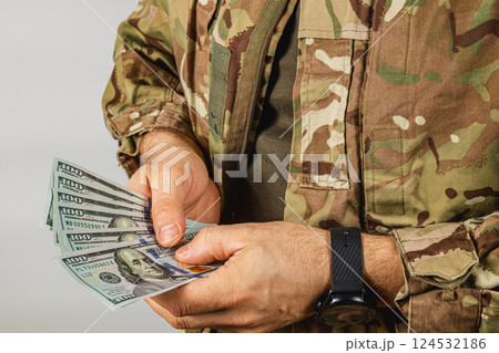 Soldier handles cash in camouflage attire at neutral location Soldier handles cash in camouflage attire at neutral location 124532186