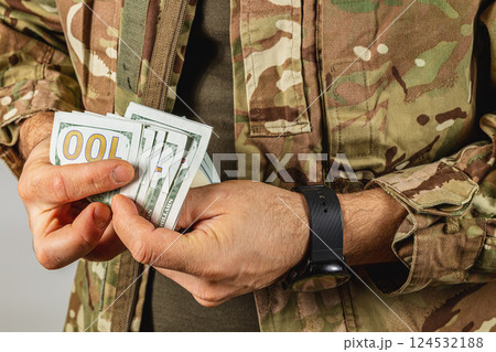 Soldier holding cash in military uniform indoors Soldier holding cash in military uniform indoors 124532188