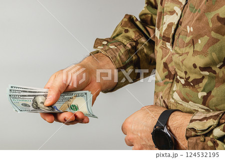 Military personnel handling cash in camouflage attire Military personnel handling cash in camouflage attire 124532195