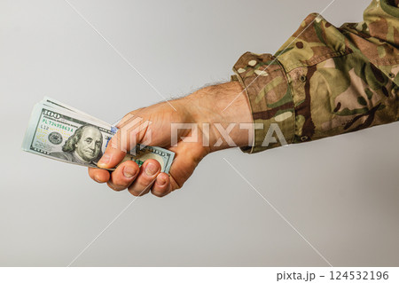 Hand holding cash with military camouflage sleeve visible Hand holding cash with military camouflage sleeve visible 124532196