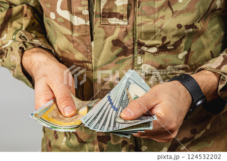 Soldier counting cash in military uniform at a neutral location Soldier counting cash in military uniform at a neutral location 124532202