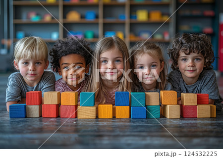 肘をついて並ぶ笑顔の子どもたちと木製ブロック 124532225