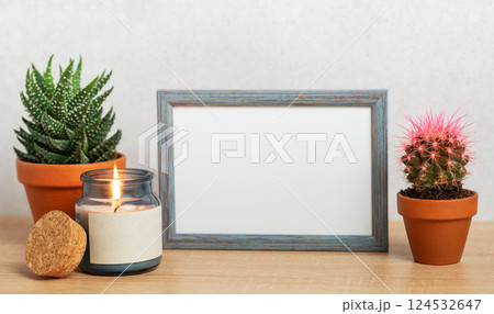 Empty frame, burning candle and succulents creating cozy home atmosphere Empty frame, burning candle and succulents creating cozy home atmosphere 124532647
