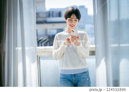 部屋でスマホを操作する女性 124532894