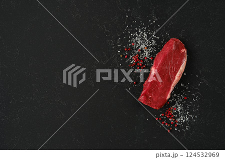 Fresh raw beef sirloin steak with spices on dark stone countertop ready for cooking Fresh raw beef sirloin steak with spices on dark stone countertop ready for cooking 124532969