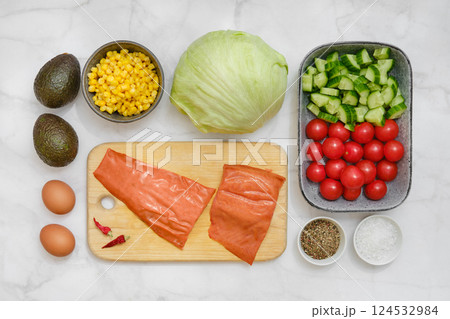 Ingredients for a fresh salad with vegetables, smoked salmon, and eggs prepared in a kitchen 124532984