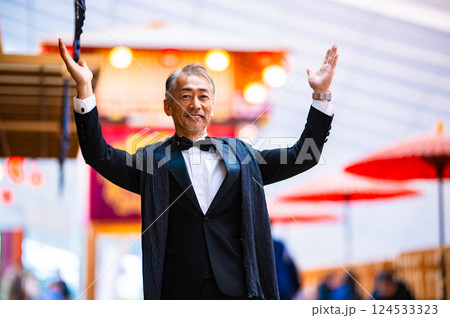 タキシードを着た両手を広げた、実業家の男性とお祭りのやぐら 124533323