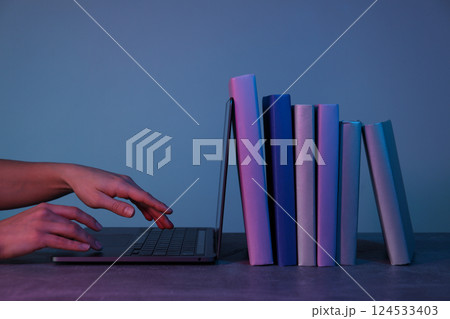 Books with a laptop on a light blue-pink background. Books with a laptop on a light blue-pink background. 124533403