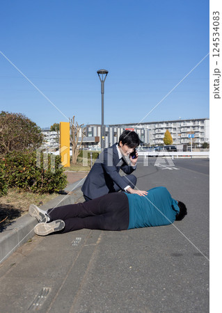 倒れている男性を救助する男性 124534083