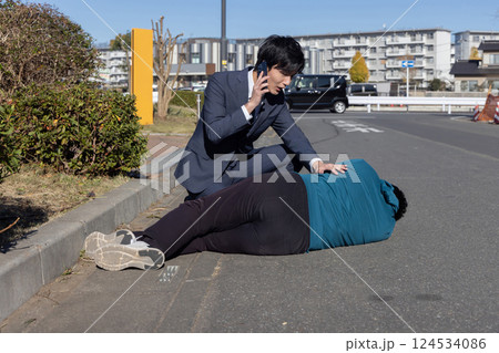倒れている男性を救助する男性 124534086