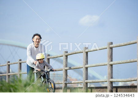 川沿いで自転車の練習をする子どもと父親 がんばれ~ 川沿いで自転車の練習をする子どもと父親 がんばれ~ 124534643
