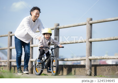 川沿いで自転車の練習をする子どもと父親 がんばれ~ 川沿いで自転車の練習をする子どもと父親 がんばれ~ 124534645