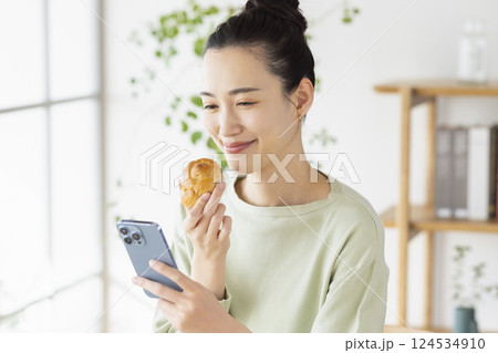 スマホを見ながら食事をとる女性 124534910