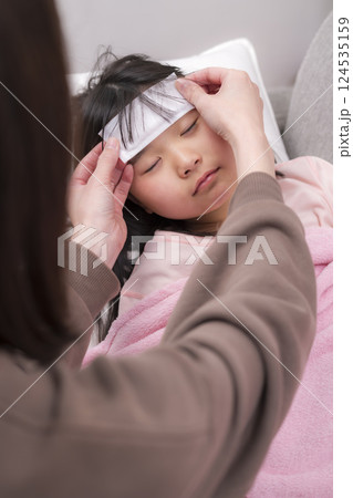 毛布にくるまって休む女の子と看病する母親 124535159