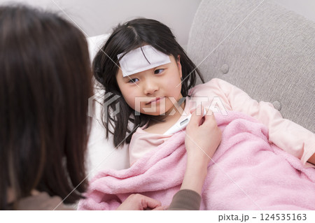 毛布にくるまって休む女の子と看病する母親 124535163