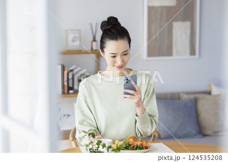 スマホを見ながら食事をとる女性 124535208