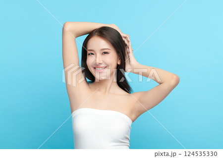 Beautiful Young Asian woman Raises her hands to Showcase clean and hygienic underarms Against a blue background, Smooth armpit cleanliness and protection concept 124535330
