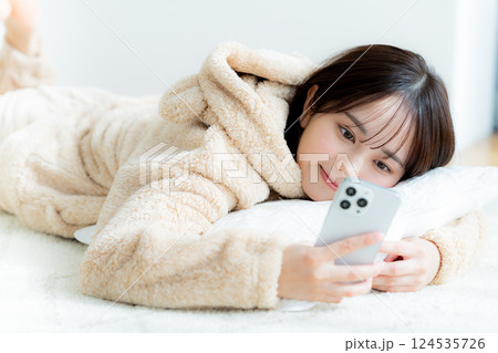部屋でスマホを操作する若い女性 124535726