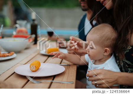 Baby girl eating corn on the cob at family barbecue gathering. 124536664