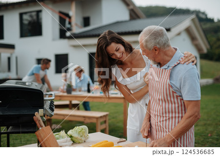 Older father and adult daughter preparing food for a family barbecue. 124536685