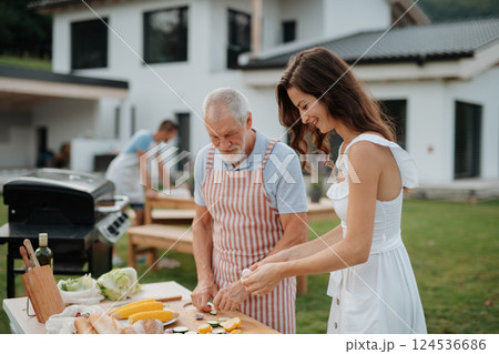 Older father and adult daughter preparing food for a family barbecue. 124536686