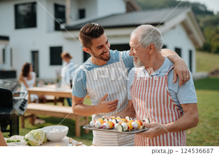 Father-in-law and son-in-law preparing food for a family barbecue. 124536687